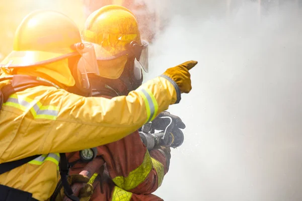 Two firefighters water spray by high pressure nozzle to fire sur — Stock Photo, Image