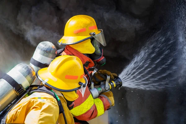 Two firefighters water spray by high pressure nozzle to fire sur — Stock Photo, Image