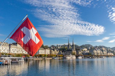 Lucerne, İsviçre - 1 Ekim 2019 - İsviçre bayrağı ve tarihi bina ve mavi gökyüzü arka planına sahip Luzern ve Reuss nehri manzarası. Lucerne, İsviçre 'nin orta kesimindeki en kalabalık kasabadır..