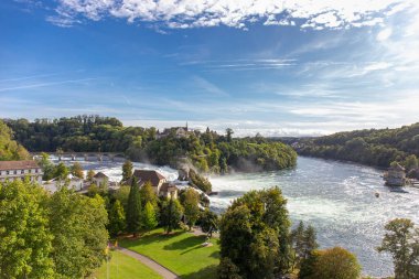 Neuhausen am Rheinfall tren istasyonundan yeşil orman ve mavi gökyüzü arkaplan manzaralı büyük ve güçlü şelale çevresi