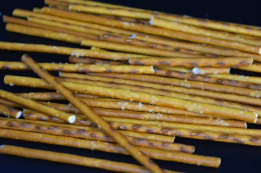 Undan yapılmış tuzlu pipetlerle lezzetli ve tuzlu pipetler, siyah plastik bir zemine saçılmış..