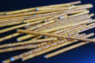 Undan yapılmış tuzlu pipetlerle lezzetli ve tuzlu pipetler, siyah plastik bir zemine saçılmış..