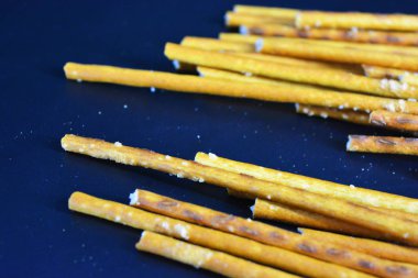 Undan yapılmış tuzlu pipetlerle lezzetli ve tuzlu pipetler, siyah plastik bir zemine saçılmış..