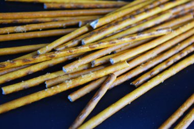 Undan yapılmış tuzlu pipetlerle lezzetli ve tuzlu pipetler, siyah plastik bir zemine saçılmış..