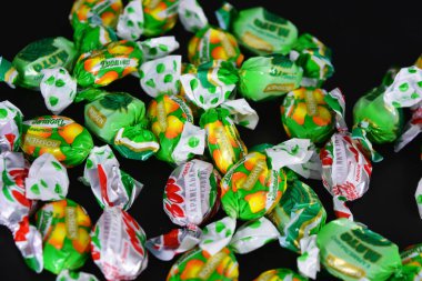 Bir sürü lezzetli şekerleme, böğürtlen, nane şekeri, düşesler siyah plastik bir arka planda yatıyor..