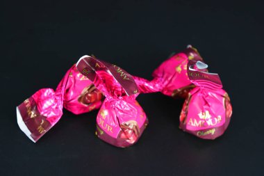 Mor ambalajlı konyak ve kirazlı tatlı ve lezzetli şekerler siyah mat plastik arka planda yer almaktadır..