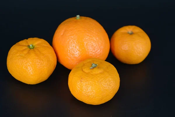 口感和健康的水果 三个橘子和一个矿物质位于黑色塑料背景 — 图库照片