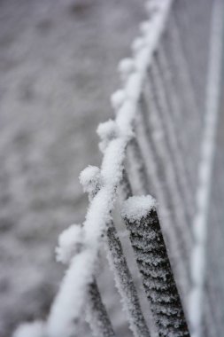 Metalik, eski, paslı, kare bir ağ, beyaz karla süslenmiş bir kafes, parlak kar toprağı ve güzel kar taneleri..