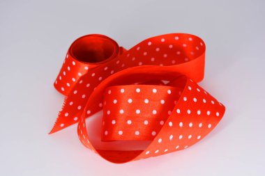 Beyaz arka planda beyaz benekli kırmızı kurdele. Geniş renkli, zarif, geniş bir kurdele ilginç bir şekilde kıvrılmış..