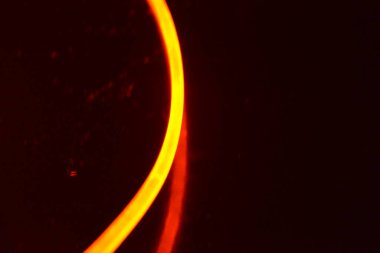 Bir ışık rehberi, turuncu ışıklı bir kablo, farklı ışık iletimli bir ışık kılavuzu, ışık tayfı ve ışık efektleri, siyah parlak arka planda ışık yansıması olan kaotik bir durumda..