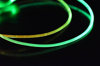 Yeşil ve kırmızı ışıklı kablo, farklı ışık iletimi, ışık spektrumuna sahip bir ışık kılavuzu kablosu ve siyah parlak arka planda ışık yansıması olan kaotik bir durumda bulunan ışık efektleri..