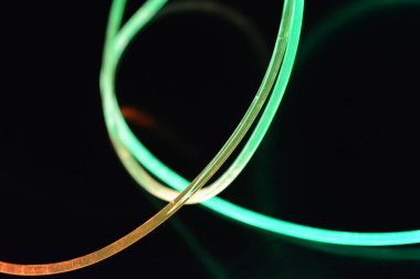 Yeşil ve kırmızı ışıklı kablo, farklı ışık iletimi, ışık spektrumuna sahip bir ışık kılavuzu kablosu ve siyah parlak arka planda ışık yansıması olan kaotik bir durumda bulunan ışık efektleri..