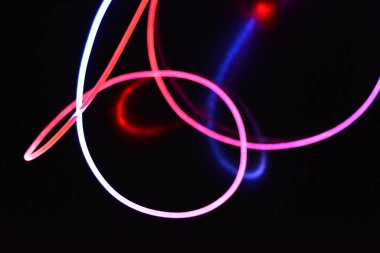 Kırmızı ve mavi ışık teli, farklı ışık iletimi, ışık spektrumu ve ışık efektleri ile siyah parlak arka planda ışık yansıması olan kaotik bir durumda..