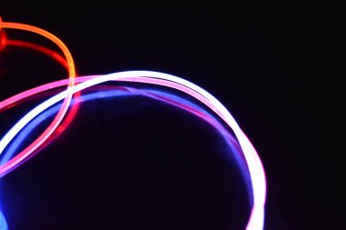 Kırmızı ve mavi ışık teli, farklı ışık iletimi, ışık spektrumu ve ışık efektleri ile siyah parlak arka planda ışık yansıması olan kaotik bir durumda..