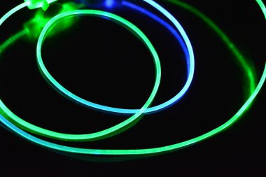 Yeşil ve mavi ışık teli, farklı ışık iletimi, ışık spektrumu ve ışık efektleri ile siyah parlak arka planda ışık yansıması olan kaotik bir durumda..