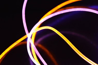 Sarı ve mavi ışık kablosu, farklı ışık iletimi, ışık spektrumu ve ışık efektleri içeren bir ışık kılavuzu kablosu, kaotik bir durumda ve siyah parlak bir arka planda ışık yansıması var..