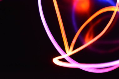 Turuncu ve mavi ışık teli, farklı ışık iletimi, ışık spektrumu ve ışık efektleri ile siyah parlak arka planda ışık yansıması olan kaotik bir durumda..