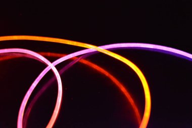 Turuncu ve mavi ışık teli, farklı ışık iletimi, ışık spektrumu ve ışık efektleri ile siyah parlak arka planda ışık yansıması olan kaotik bir durumda..