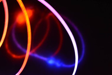 Turuncu ve mavi ışık teli, farklı ışık iletimi, ışık spektrumu ve ışık efektleri ile siyah parlak arka planda ışık yansıması olan kaotik bir durumda..