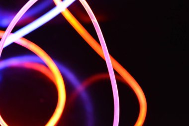 Turuncu ve mavi ışık teli, farklı ışık iletimi, ışık spektrumu ve ışık efektleri ile siyah parlak arka planda ışık yansıması olan kaotik bir durumda..