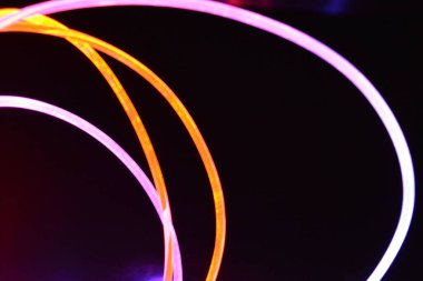 Turuncu ve mavi ışık teli, farklı ışık iletimi, ışık spektrumu ve ışık efektleri ile siyah parlak arka planda ışık yansıması olan kaotik bir durumda..