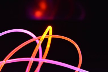 Turuncu ve mavi ışık teli, farklı ışık iletimi, ışık spektrumu ve ışık efektleri ile siyah parlak arka planda ışık yansıması olan kaotik bir durumda..