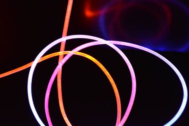 Turuncu ve mavi ışık teli, farklı ışık iletimi, ışık spektrumu ve ışık efektleri ile siyah parlak arka planda ışık yansıması olan kaotik bir durumda..