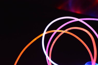 Turuncu ve mavi ışık teli, farklı ışık iletimi, ışık spektrumu ve ışık efektleri ile siyah parlak arka planda ışık yansıması olan kaotik bir durumda..