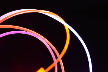 Turuncu ve mavi ışık teli, farklı ışık iletimi, ışık spektrumu ve ışık efektleri ile siyah parlak arka planda ışık yansıması olan kaotik bir durumda..