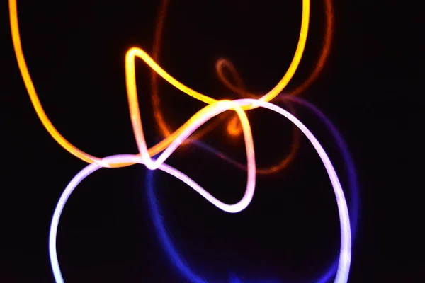 Yellow and blue light wire, a light guide wire with different light transmission, light spectrum, and light effects located in a chaotic state with light reflection on a black glossy background.