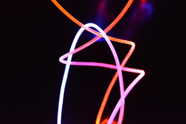 Orange and blue light wire, a light guide wire with different light transmission, light spectrum, and light effects located in a chaotic state with light reflection on a black glossy background.