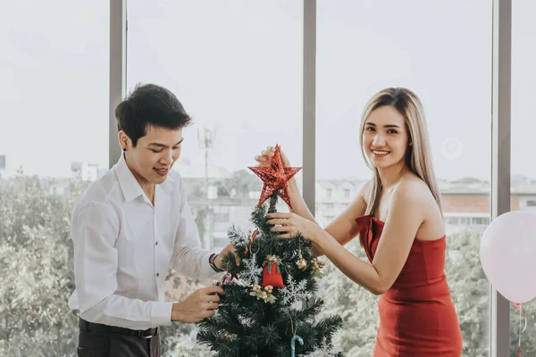 Joven pareja asiática decorando árbol de Navidad juntos en casa, h —  Fotos de Stock