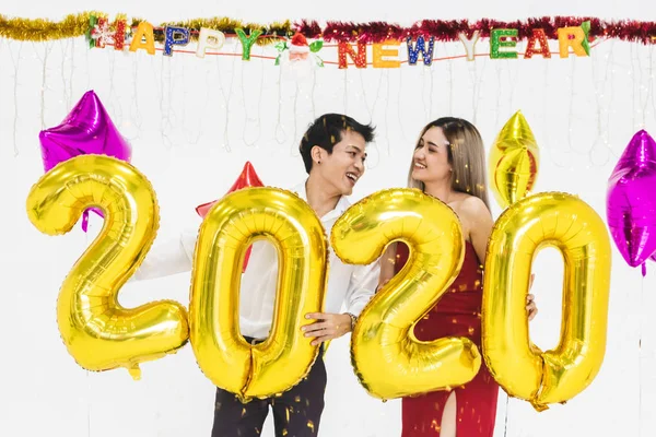 Pareja joven celebrando año nuevo juntos, la celebración de 2020 globo —  Fotos de Stock