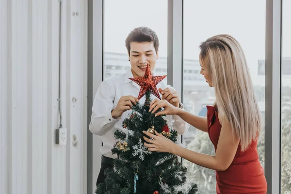 Joven pareja asiática decorando árbol de Navidad juntos en casa, h —  Fotos de Stock