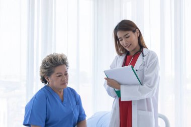 Genç çekici Asyalı doktor hastaya semptomlarını, sağlık bakımını ve hastane konseptini anlatıyor..