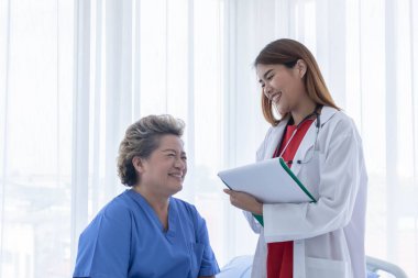 Genç çekici Asyalı doktor hastaya semptomlarını, sağlık bakımını ve hastane konseptini anlatıyor..