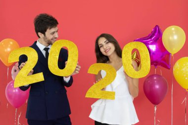 Genç çift yeni yılı birlikte kutluyor, ellerinde kırmızı arkaplanlı 2020 adet simli mektup var..