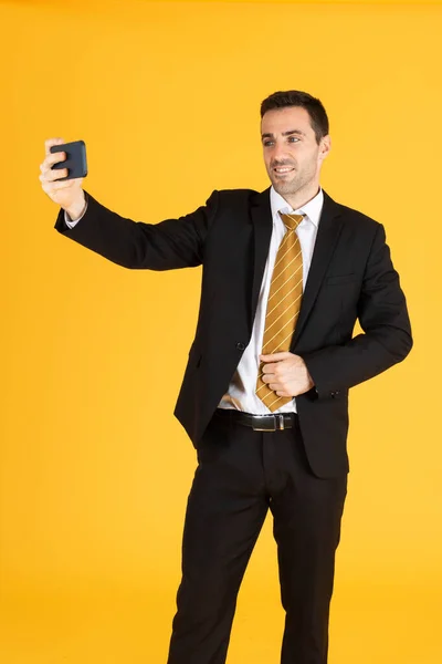 Portret Pewnego Siebie Biznesmena Używającego Smartfona Robienia Selfie Żółtym Tle — Zdjęcie stockowe