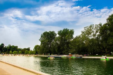 Yeşil bir parkta dinlenmek için katamaran göleti