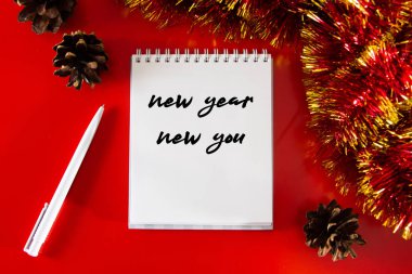 Yeni yıl için hedefleri ve planları olan bir not. Noel dekorunun arka planında tasarım düzeni.