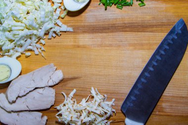 Sağlıklı bir diyet için lezzetli bir salata hazırlama süreci. Ahşap zemin üzerinde salata malzemeleri ve bıçak..