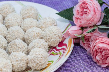 Hindistan cevizli tatlı toplar ve pembe çiçeklerle dolu bir tabak. Sevgililer Günü için şekerler.