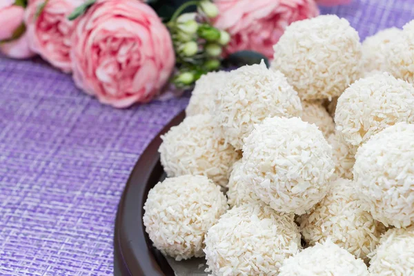 Coconut candy pyramid on a background of flowers close-up