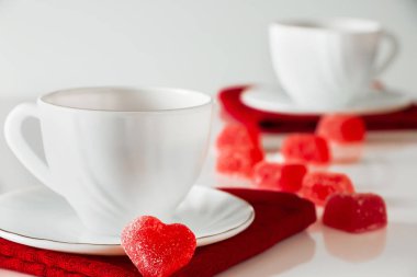 Beyaz arka planda iki beyaz fincan çay. Kalp şeklinde marmelat, Sevgililer Günü ve aşkın sembolü. İki aşığın buluşması konsepti.