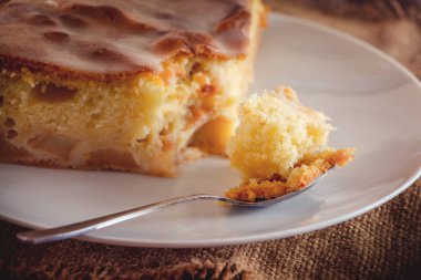 Bir kaşık üzerinde elmalı turta, keten arka planda yakın plan.