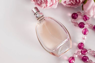 Beyaz arka planda parfüm şişesi ve çiçekler. Kadınlar Günü için hediye konsepti. Açık pembe arka planda hoş kokulu parfüm. Pastel renkler, metin için yer.