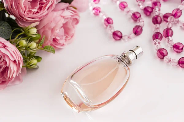 Perfume bottle and flowers on a white background. Holiday gift - perfume bottle and flowers on a white background