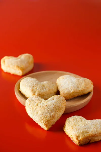 Heart shaped sugar cookies on red background. Sugar cookies hearts on a wooden plate on a red background.