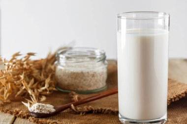 Beyaz arka planda bir bardak yulaf sütü. Laktozsuz sebze diyeti sütü. Açık beyaz arka planda glütensiz yulaf içeceği. Süper Yemek - Sağlıklı bir diyet için bir bardak yulaf sütü. Moda yemek, dikey fotoğraf. Metnin için yer.