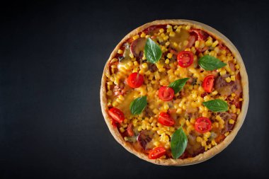Siyah arka planda domatesli ve fesleğenli büyük İtalyan pizzası. Siyah arka planda vişneli, peynirli ve yeşil fesleğenli büyük pizza. Ulusal İtalyan yemeği Akdeniz mutfağı. Üst görünüm, metin için yer.